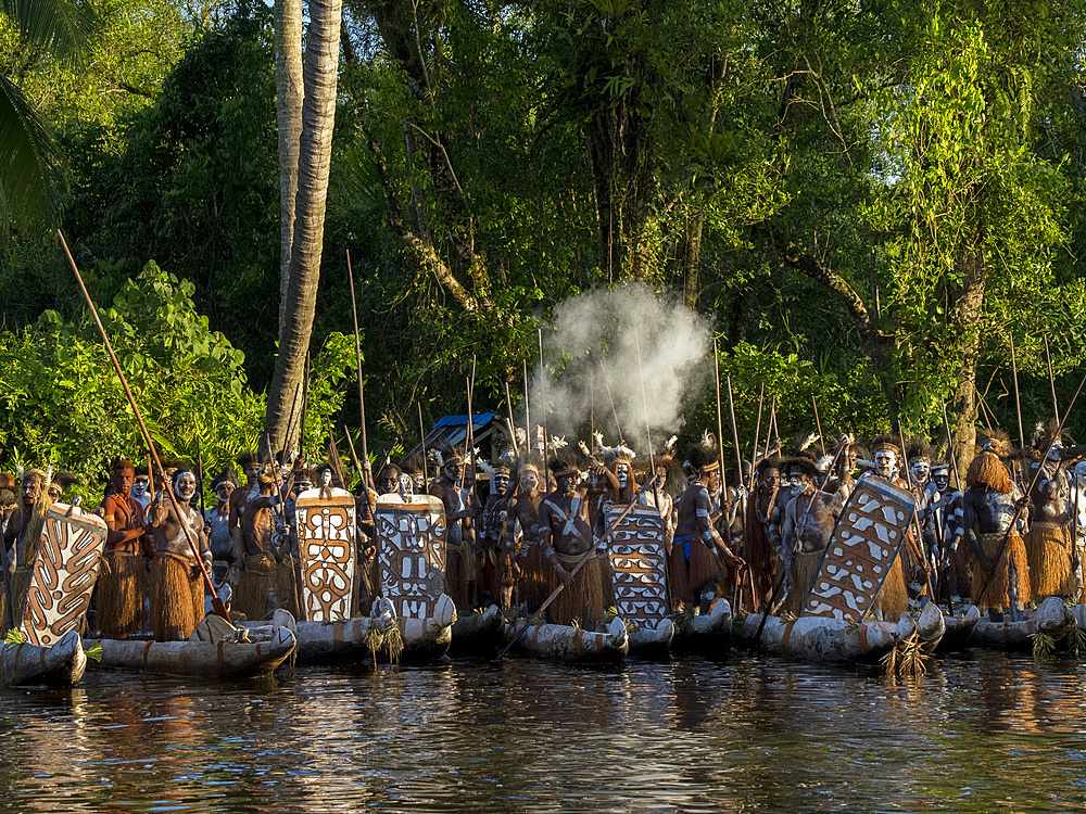 Male paddlers from the village of Per perform in a ritualistic greeting ceremony, Asmat Region, Papua, Indonesia.
