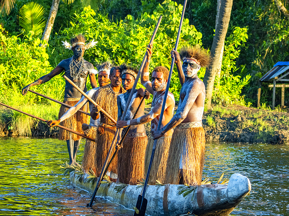 Male paddlers from the village of Uwus perform in a ritualistic greeting ceremony, Asmat Region, Papua, Indonesia.