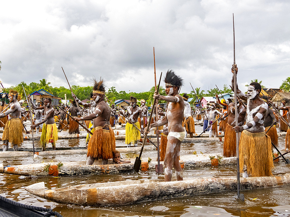 Male paddlers from the village of Uwus perform in a ritualistic greeting ceremony, Asmat Region, Papua, Indonesia.
