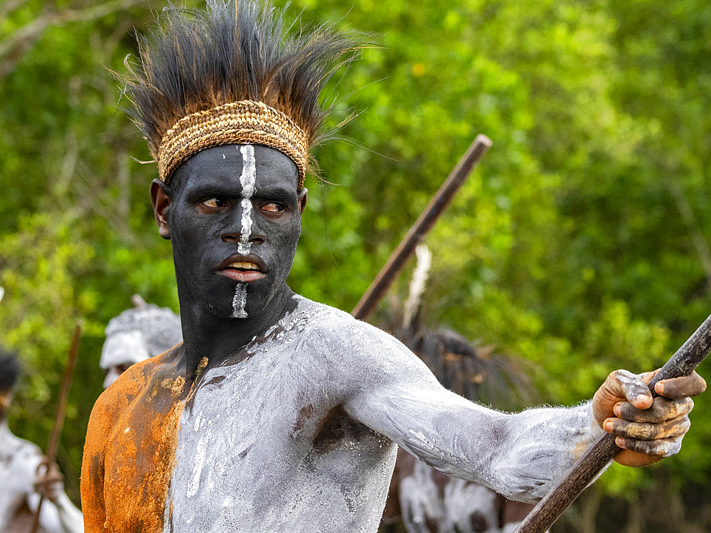 Male paddlers from the village of Uwus perform in a ritualistic greeting ceremony, Asmat Region, Papua, Indonesia.