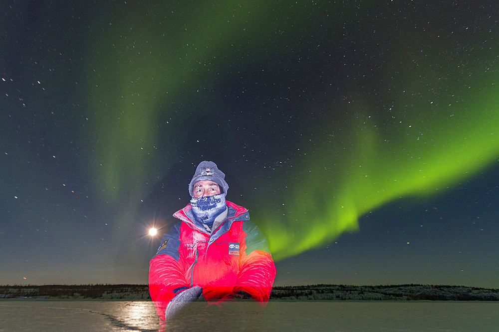 Long exposure of myself with Aurora Borealis, or Northern Lights, the Great Slave Lake, Northwest Territories, Canada.