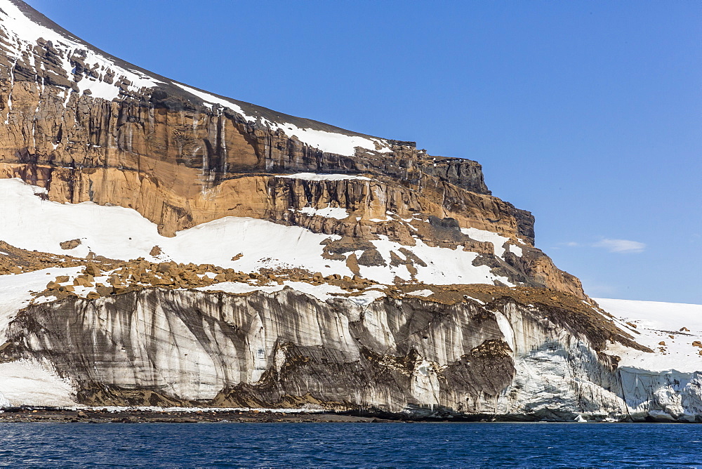 Rust-colored volcanic tuff cliffs above a dark material filled glacier at Brown Bluff, eastern side of the Tabarin Peninsula, Weddell Sea, Antarctica, Polar Regions