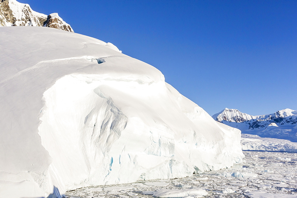 Snow-covered mountains line the ice floes in Penola Strait, Antarctica, Polar Regions