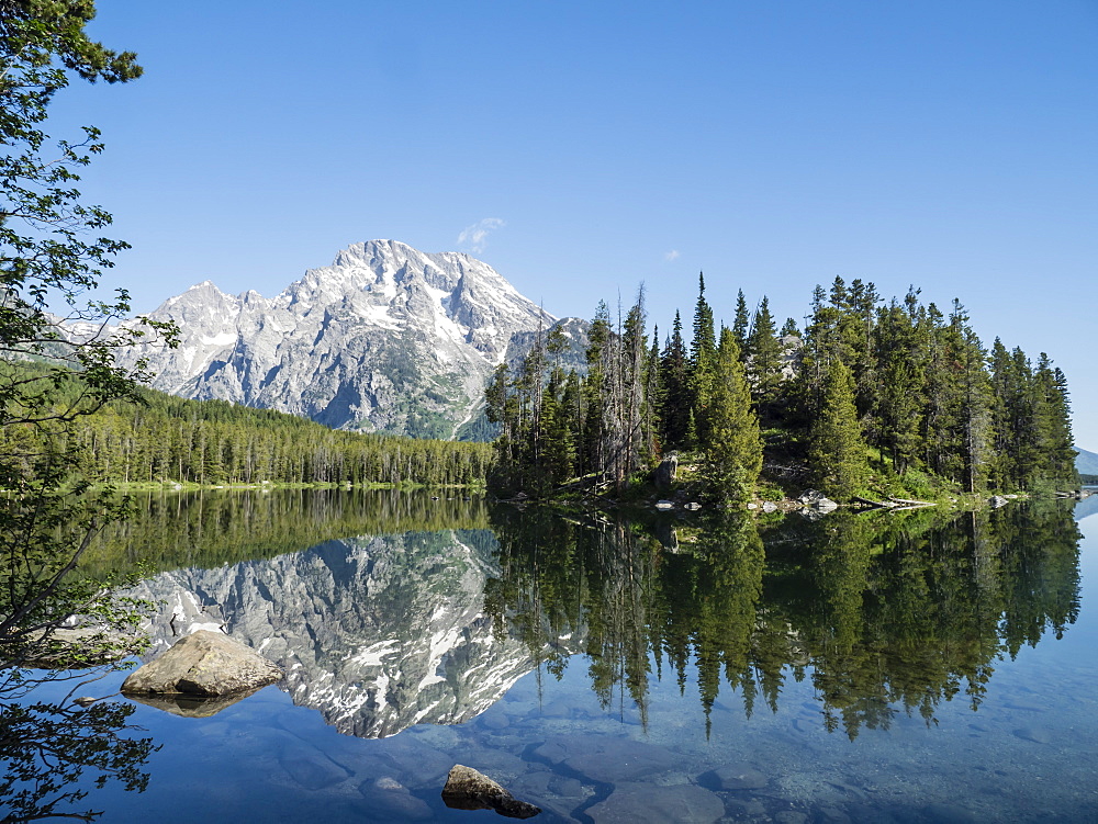 Snow-capped mountains reflected in the calm waters of Leigh Lake, Grand Teton National Park, Wyoming, United States of America, North America