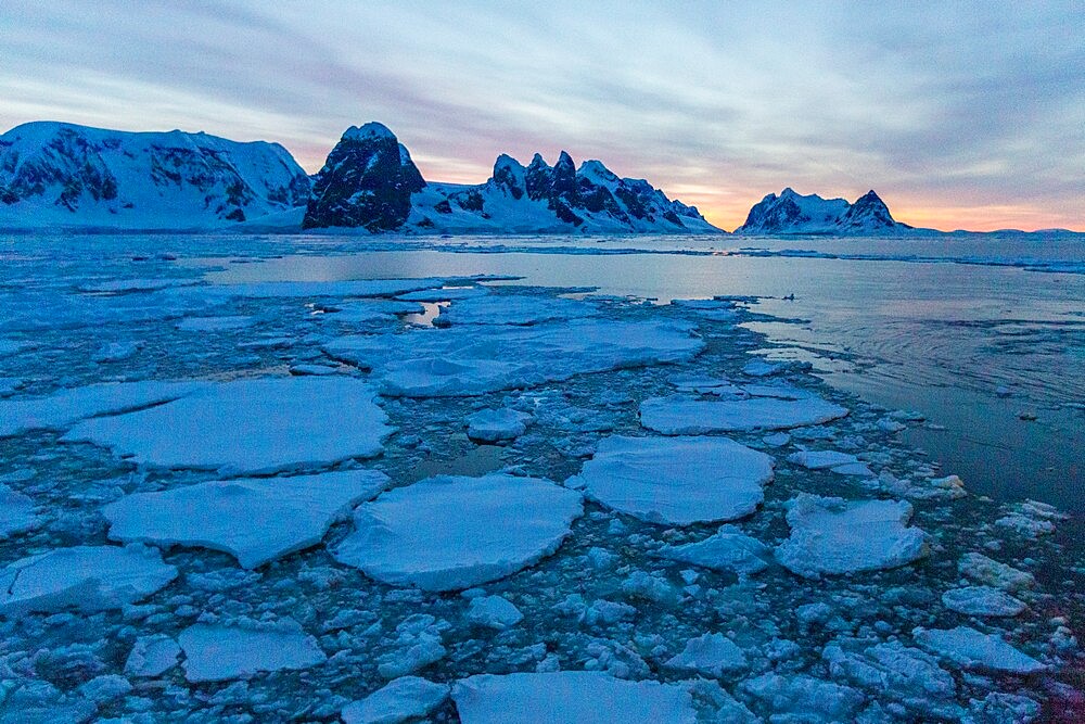 Sunrise on snow-covered mountains and dense sea ice in Neumayer Channel, Palmer Archipelago, Antarctica, Polar Regions