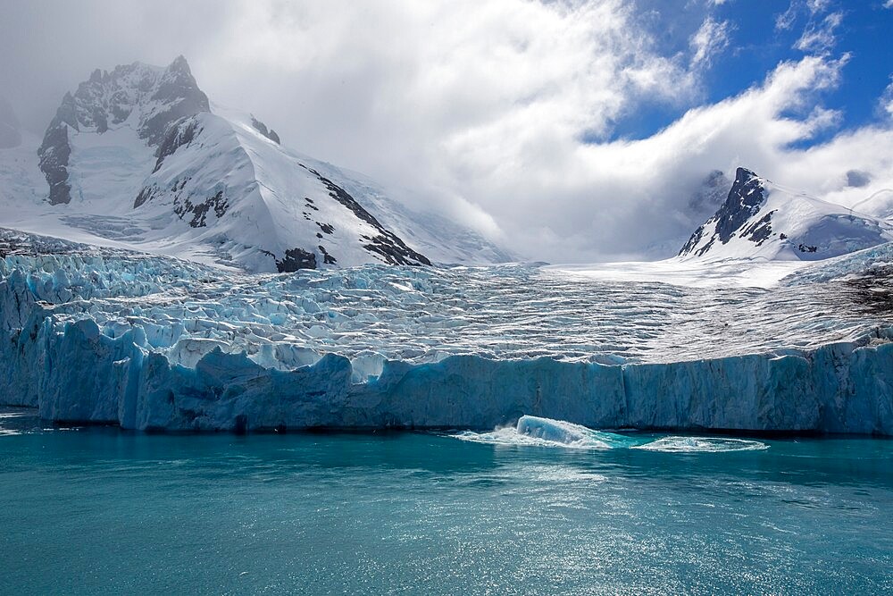 A view of snow-capped mountains and a shooter from the glacier in Drygalski Fjord, South Georgia, South Atlantic, Polar Regions