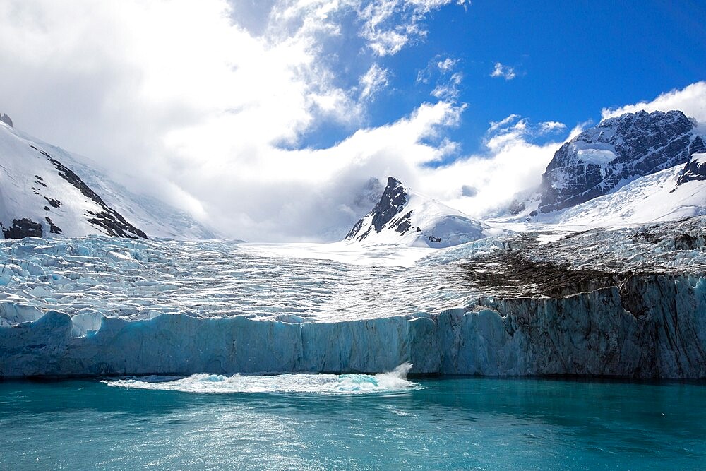 A view of snow-capped mountains and a shooter from the glacier in Drygalski Fjord, South Georgia, South Atlantic, Polar Regions