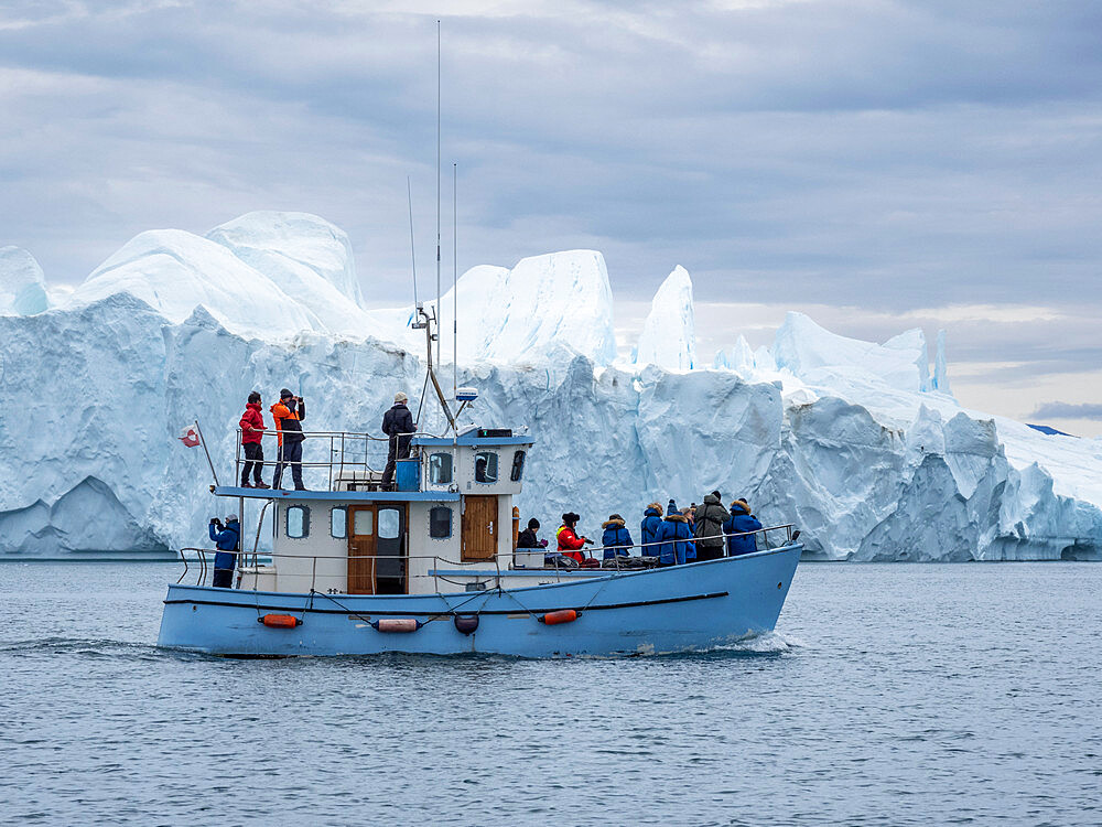 Tourists taking an ice tour in a small boat watching icebergs from the Ilulissat Icefjord, just outside Ilulissat, Greenland, Denmark, Polar Regions