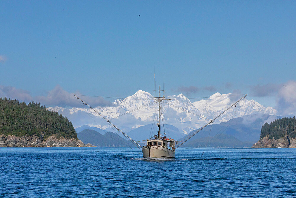 Commercial fishing boat in Inian Pass with the Fairweather Mountains behind, Southeast Alaska, USA.