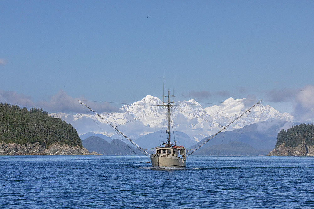 Commercial fishing boat in Inian Pass with the Fairweather Mountains behind, Southeast Alaska, USA.