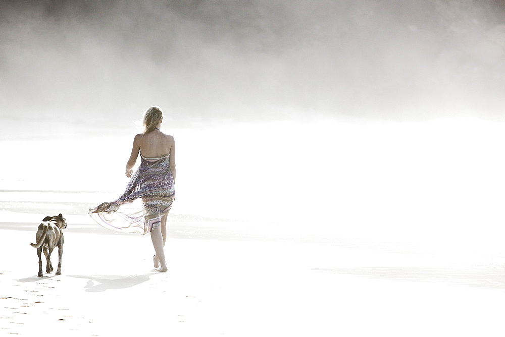 Young woman walking at the beach with a dog, Fuerteventura, Spain