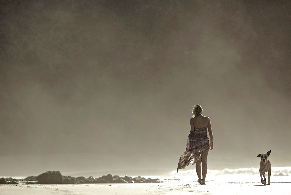 Young woman walking at the beach with a dog, Fuerteventura, Spain