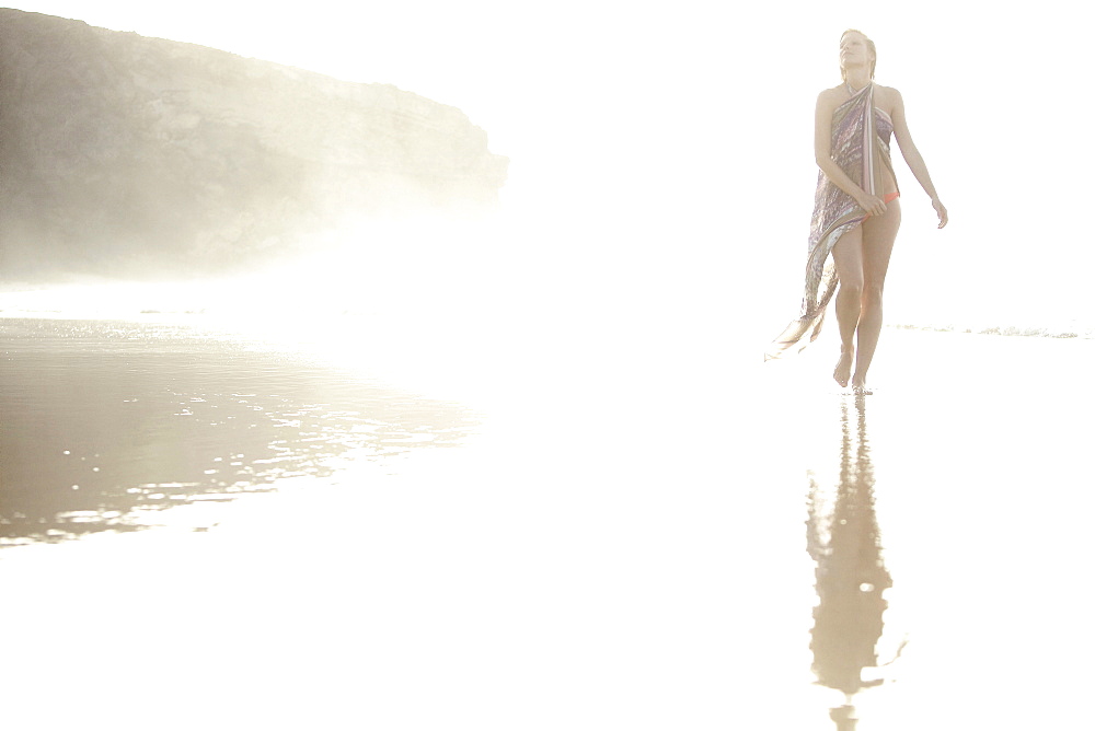 Young woman walking through shallow water at beach, Fuerteventura, Spain