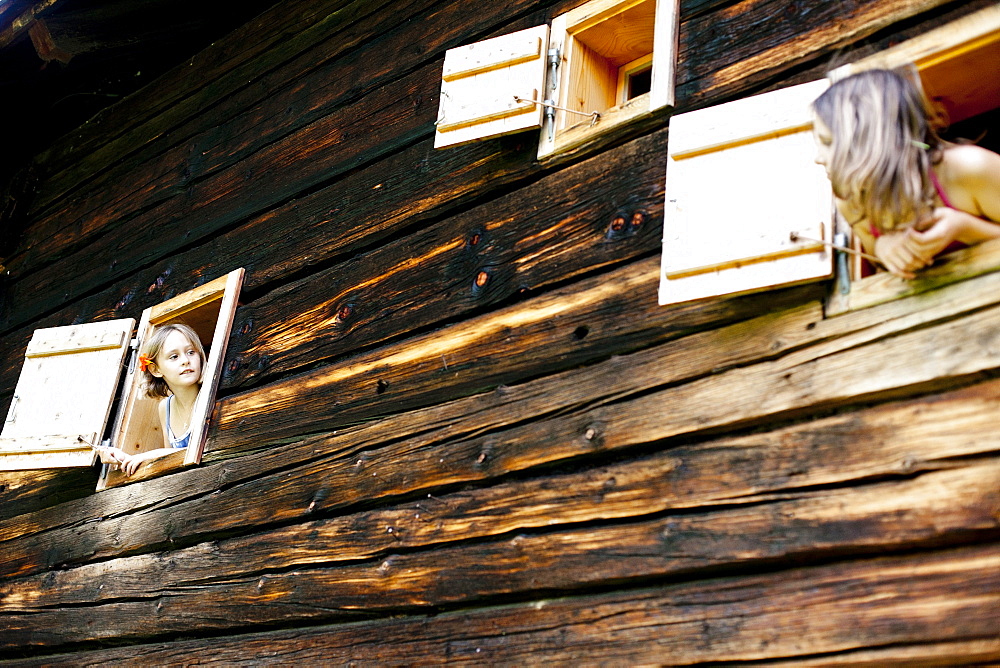 Two girls looking out of farmhouse, Styria, Austria