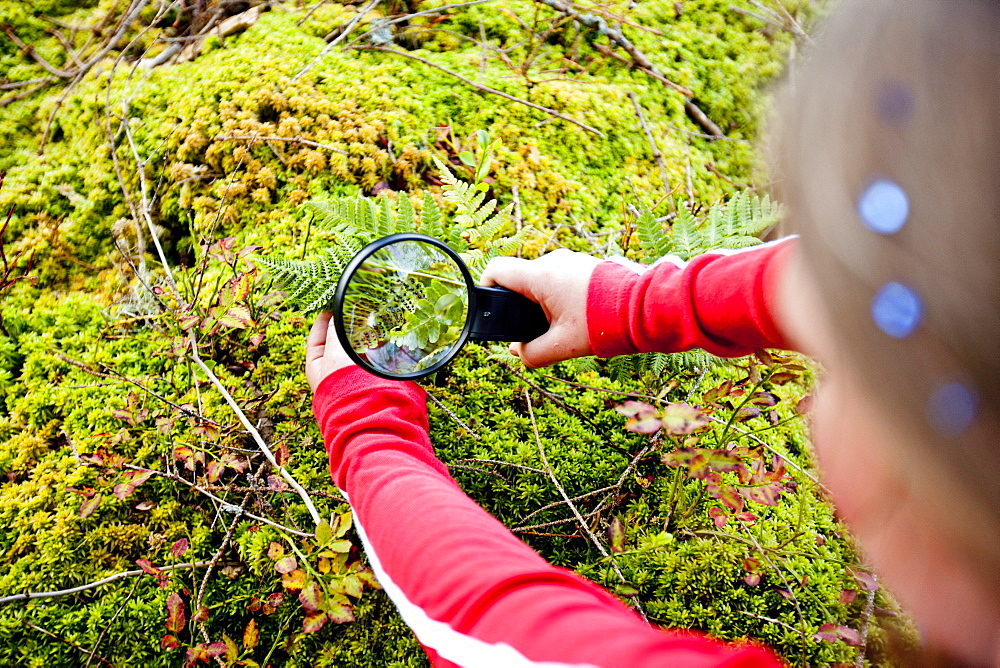 Girl looking at plant through magnifying glass, Styria, Austria