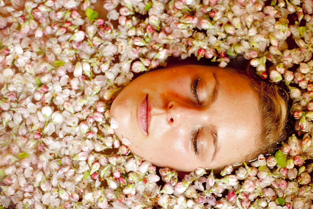 Young woman enjoying an apple blossoms bath, Stubenberg, Styria, Austria