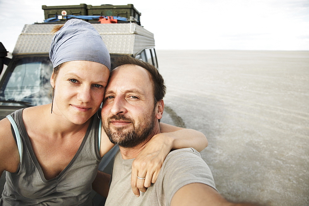 Couple posing in front of an off-road vehicle, Kubu Island, Makgadikgadi Pan, Botswana