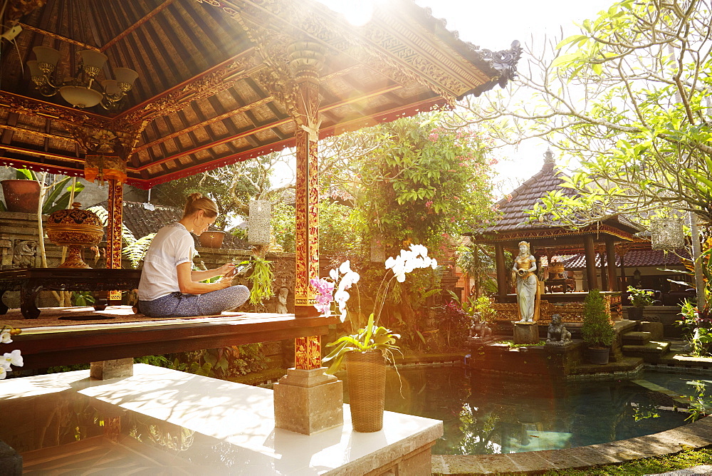 Woman sitting in a pavilion while reading, Ubud, Bali, Indonesia