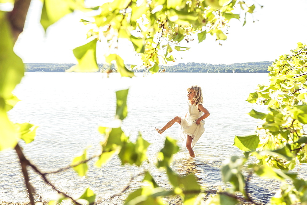 Girl wearing a summerdress standing in lake Starnberg, Berg, Upper Bavaria, Germany