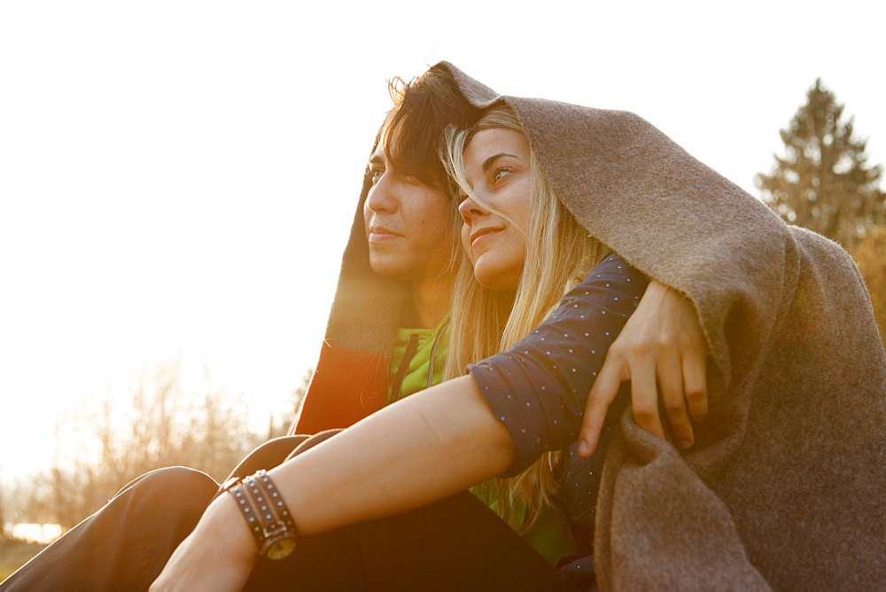 Young couple wrapped in a blanket, Grosser Alpsee, Immenstadt, Bavaria, Germany