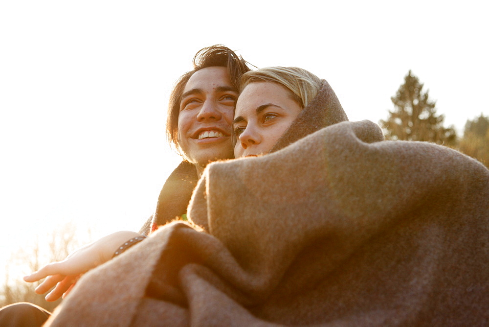 Young couple wrapped in a blanket, Grosser Alpsee, Immenstadt, Bavaria, Germany