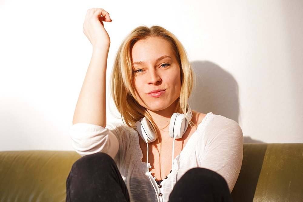 Young woman sitting on the sofa, daydreaming