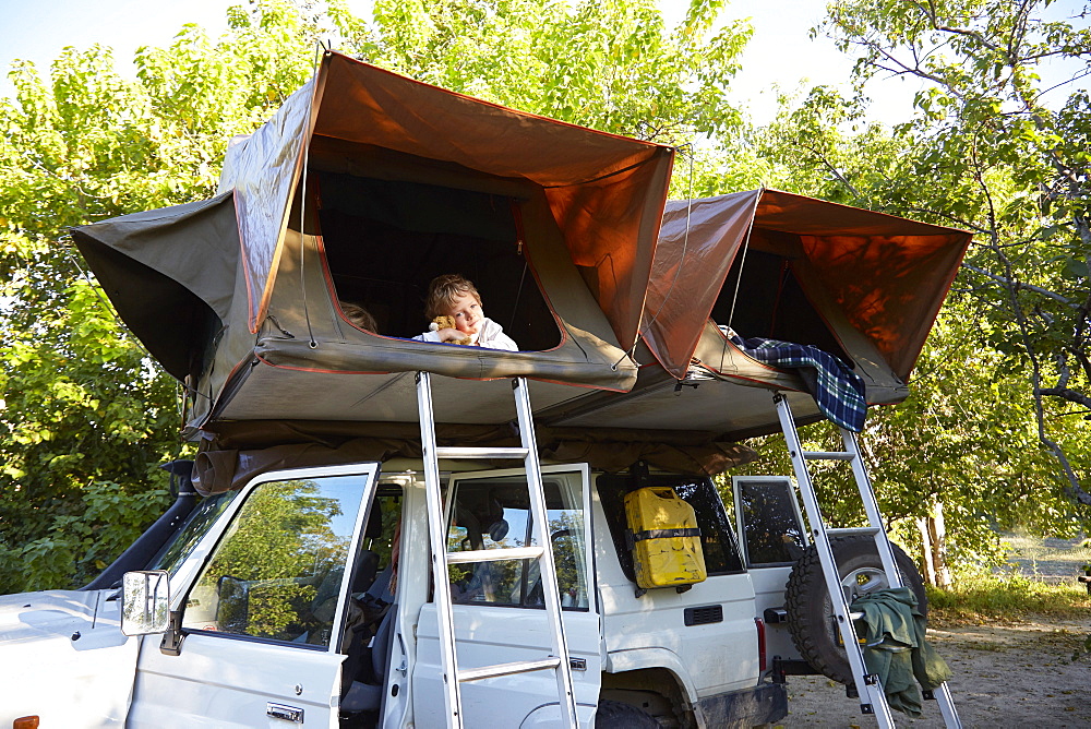 Boy inside a roof tent, Maun, Okavango Delta, Botswana