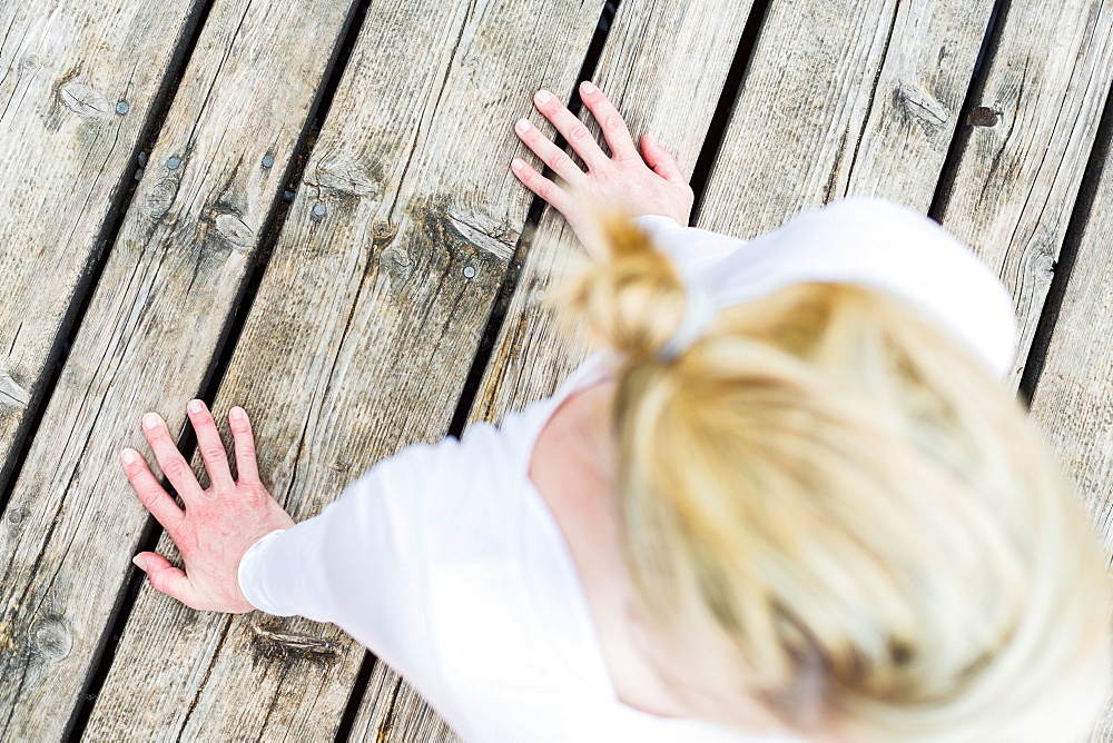 woman doing yoga on the wooden jetty, sun salute, Kirchsee, Bad Toelz, Bavaria, Germany