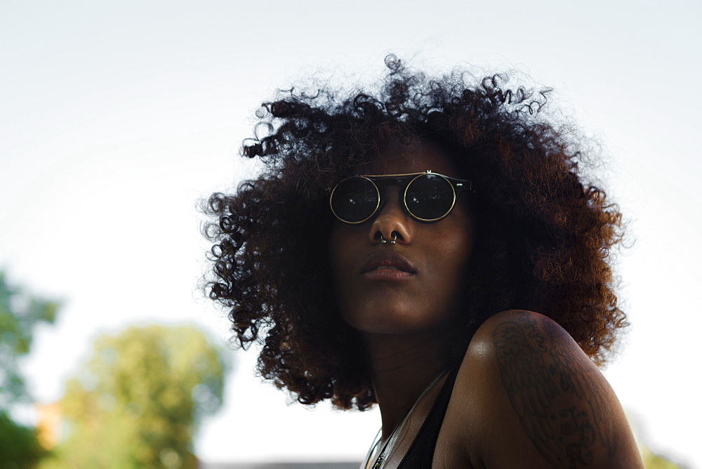 Portrait of a young afro-american woman with sunglasses and blue sky, Munich, Bavaria, Germany