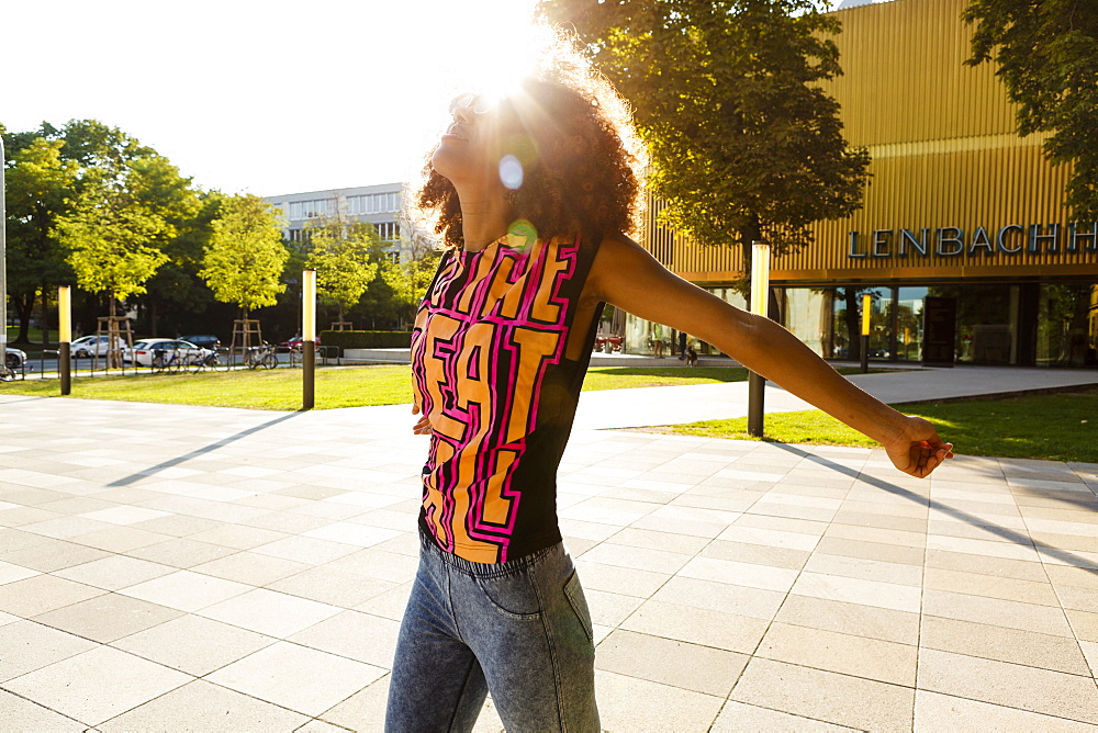 Young afro-american woman enjoying the sunshine at Lenbachplatz, Munich, Bavaria, Germany