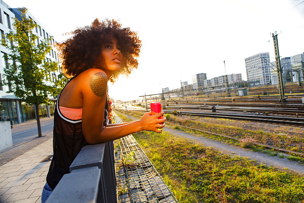 Young afro-american woman relaxed in urban scenery with backlight, Hackerbruecke Munich, Bavaria, Germany