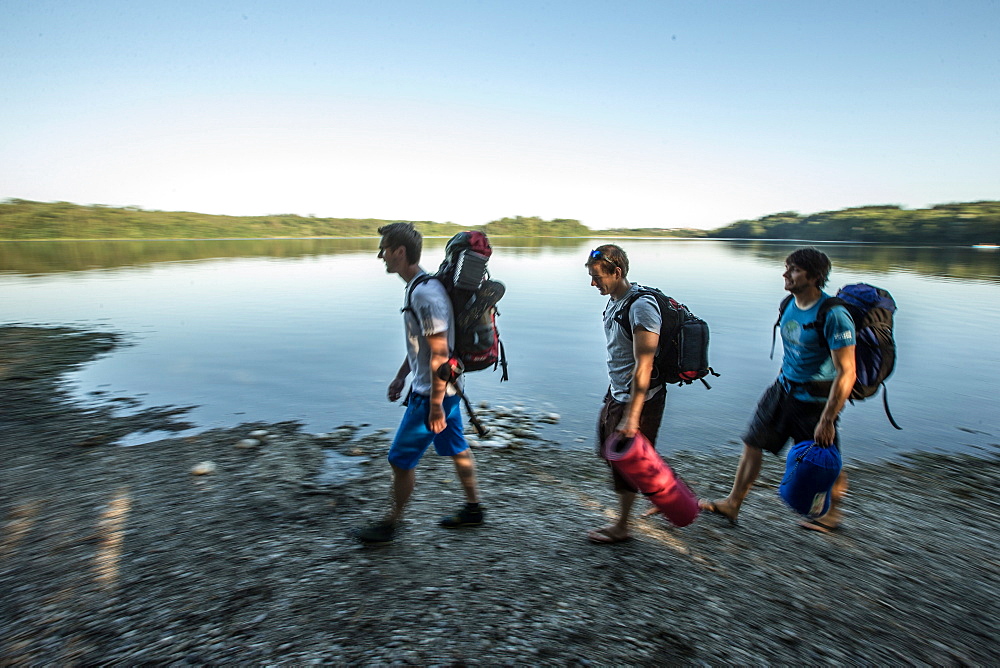 Three young male camper walking at a lake, Freilassing, Bavaria, Germany