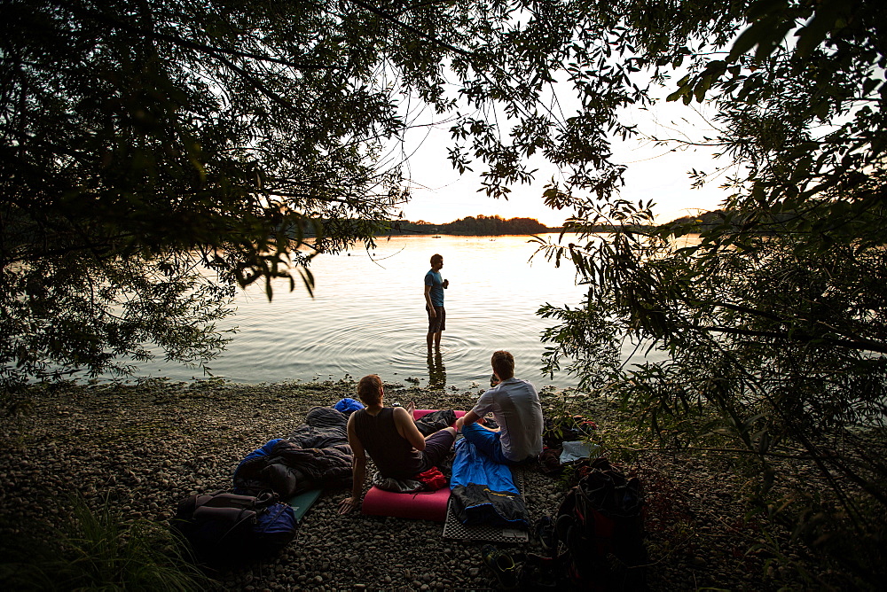 Three young men camping at a lake, Freilassing, Bavaria, Germany