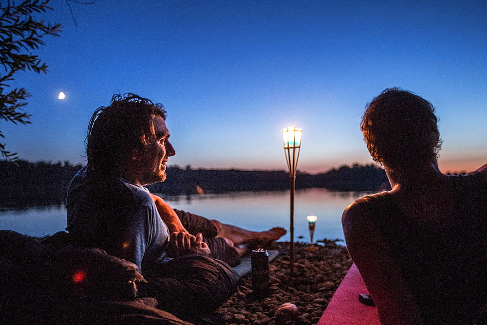 Two young men lying at a lake at night, Freilassing, Bavaria, Germany