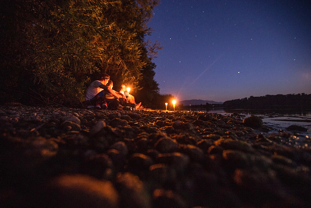 Three young man sitting at a lake at night, Freilassing, Bavaria, Germany