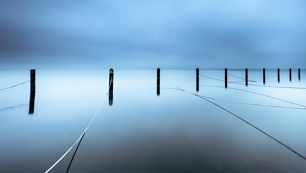 Foggy winter morning in abandoned marina, wooden posts in Lake Starnberg, Seeshaupt, Bavaria, Germany