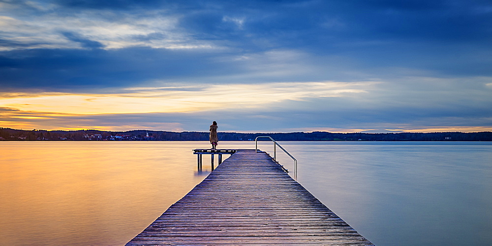 Woman on jetty at sunset on Lake Starnberg, St. Heinrich, Bavaria, Germany