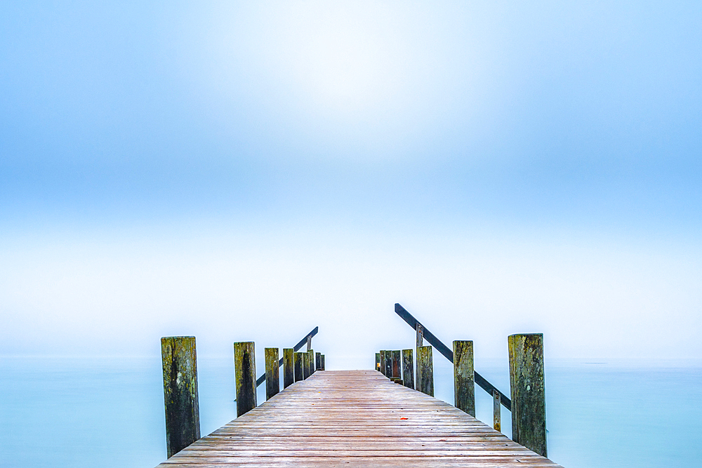 Jetty on Lake Starnberg in autumn morning fog, Garatshausen, Bavaria, Germany