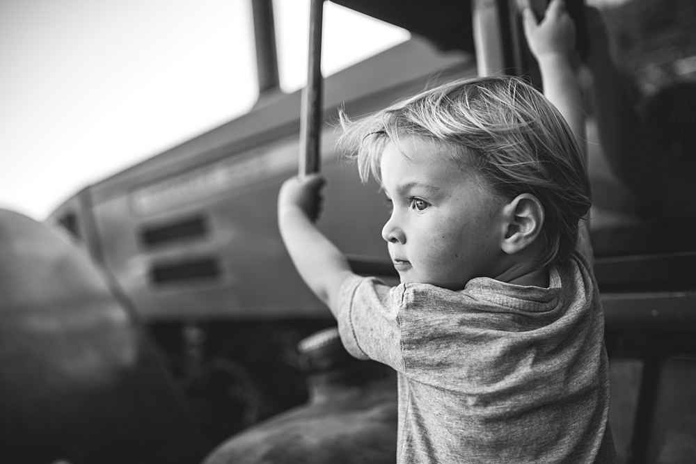 Boy climbs on a tractor, black and white