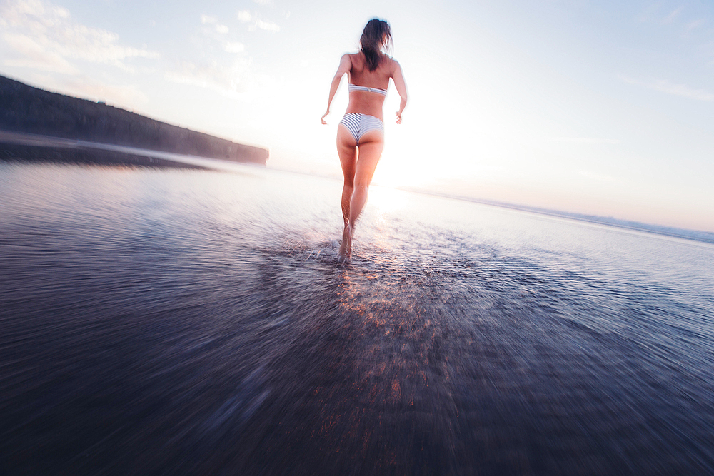 Woman running in bikni over the beach in the evening, Portugal, vacation