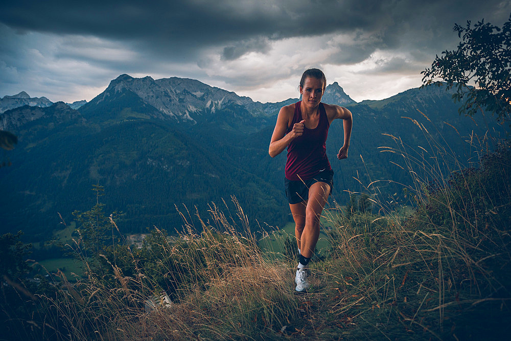 Young woman runs in the evening mood at Falkenstein, Allgäu, Bavaria, Germany