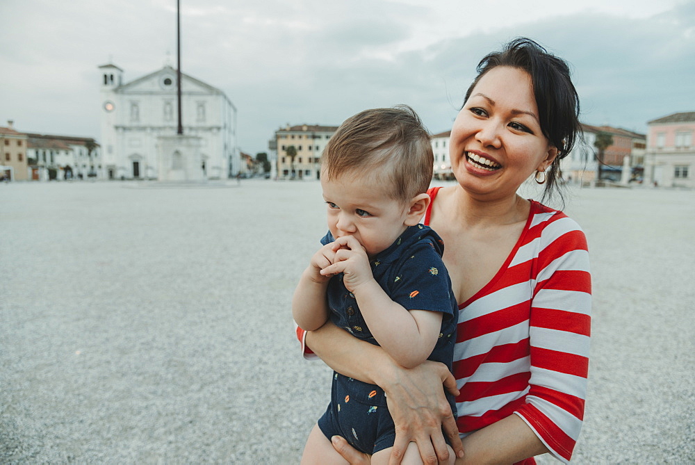 A woman holding a baby boy at the beach, Italy