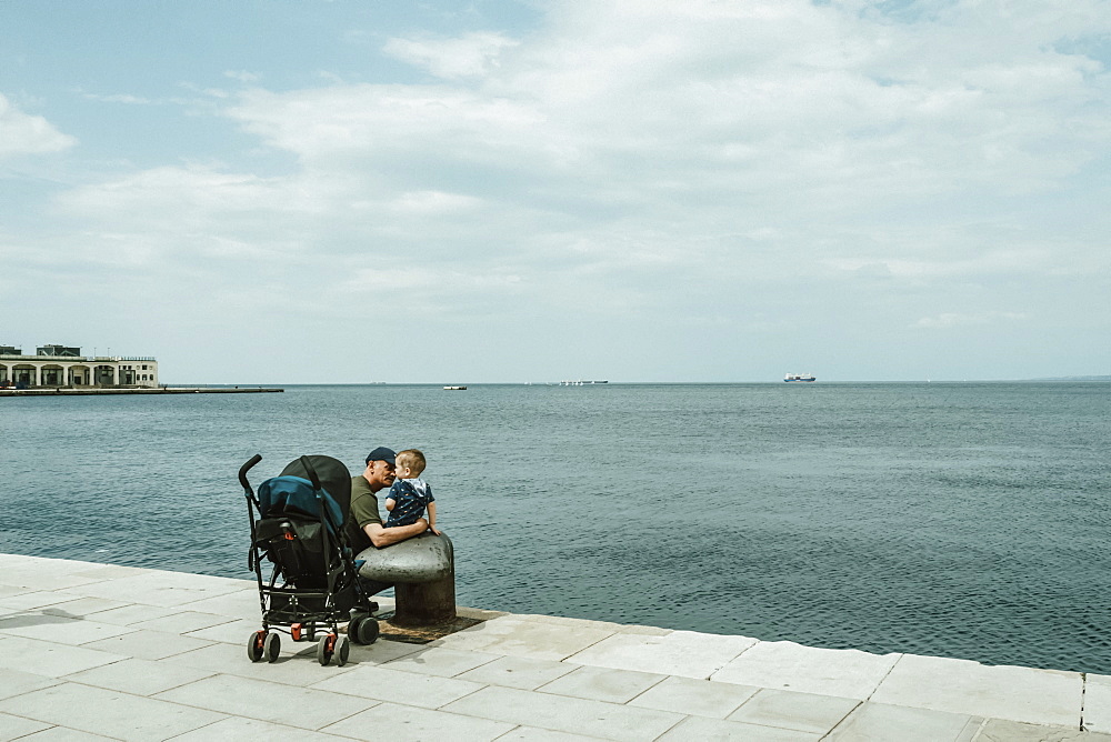 Father and baby boy on a waterfront promenade on the Adriatic Sea, Italy