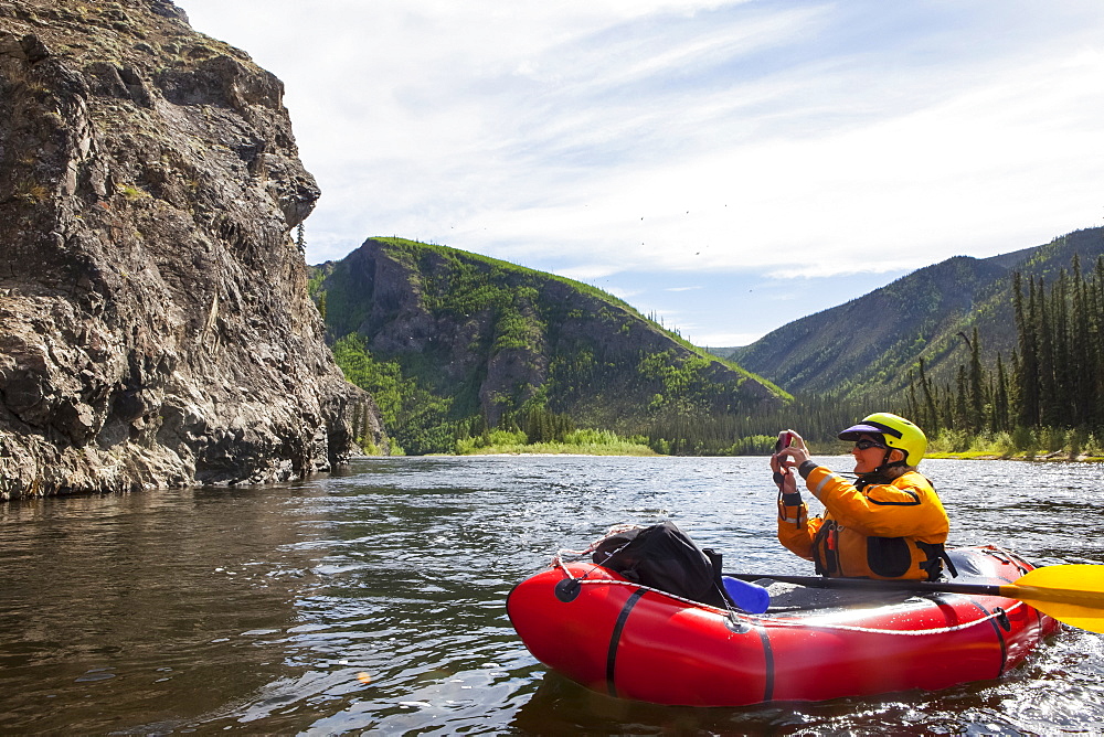 Woman photographing from her Packrafting on the Charley River in summertime, Yukon–Charley Rivers National Preserve, Alaska, United States of America