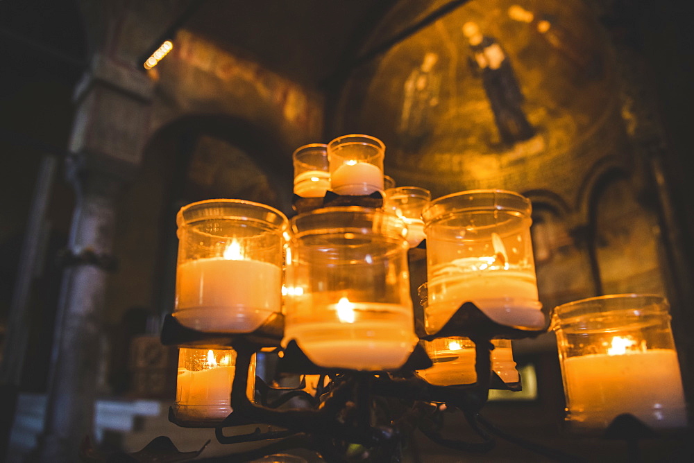 Lit candles and artwork in a cathedral, Italy