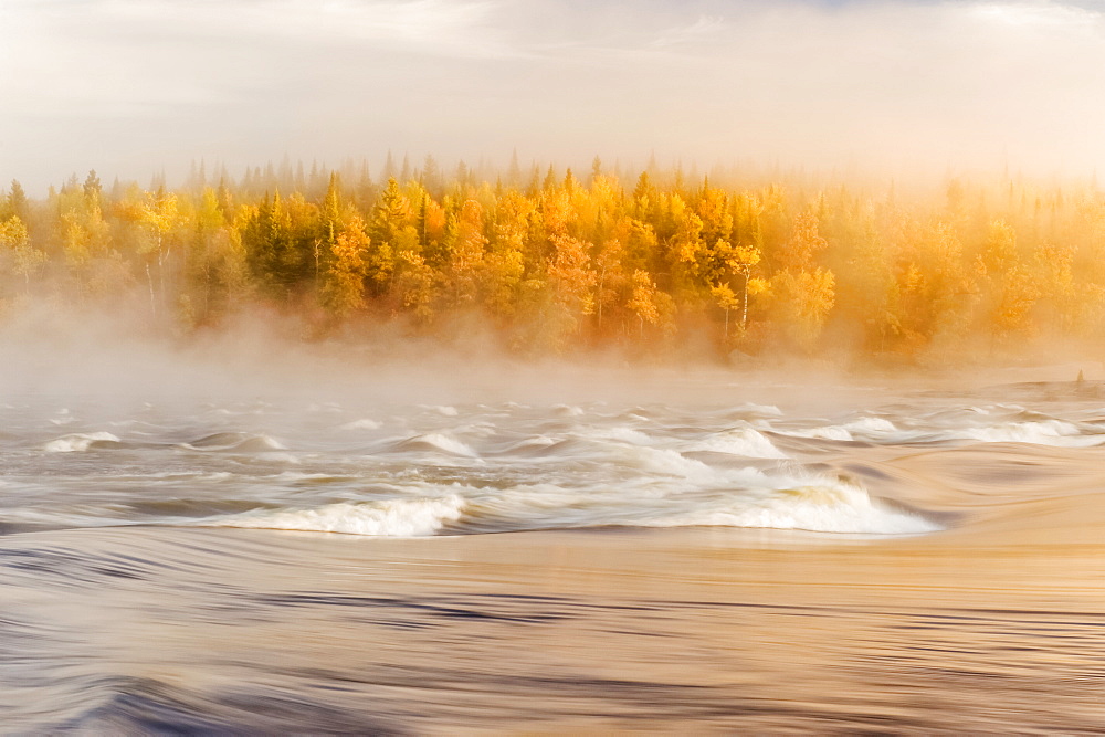 Flowing water with fog settled over a river and autumn coloured forest, Sturgeon Falls, Whiteshell Provincial Park, Manitoba, Canada