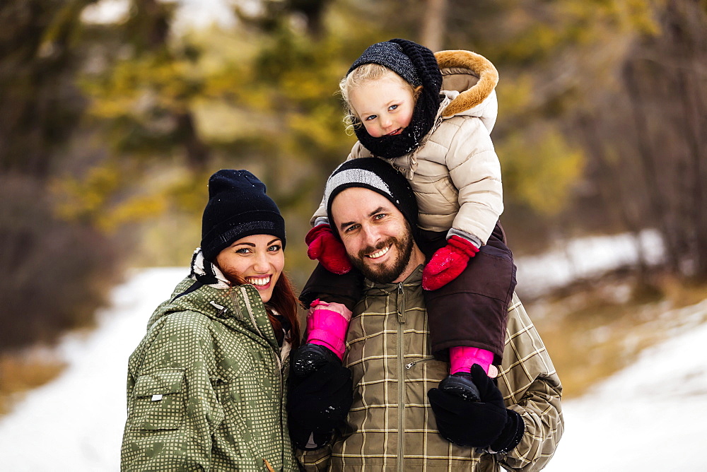 A young family hiking outdoors with their young daughter during a winter family outing: Fairmont, British Columbia, Canada