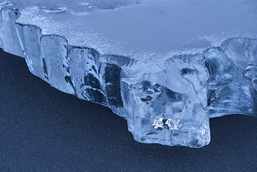 Close-up of a piece of ice sitting in the black sand on the South shore of Iceland, Iceland