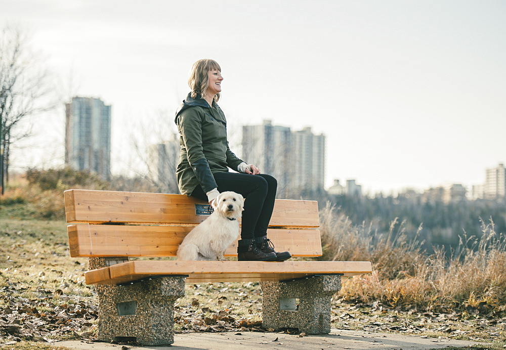 Woman out with her dog with a city skyline in the background, Edmonton, Alberta, Canada