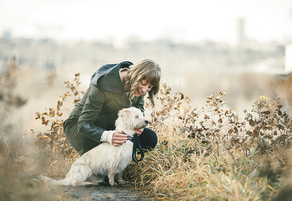 Woman walking her dog with a city skyline in the background, Edmonton, Alberta, Canada